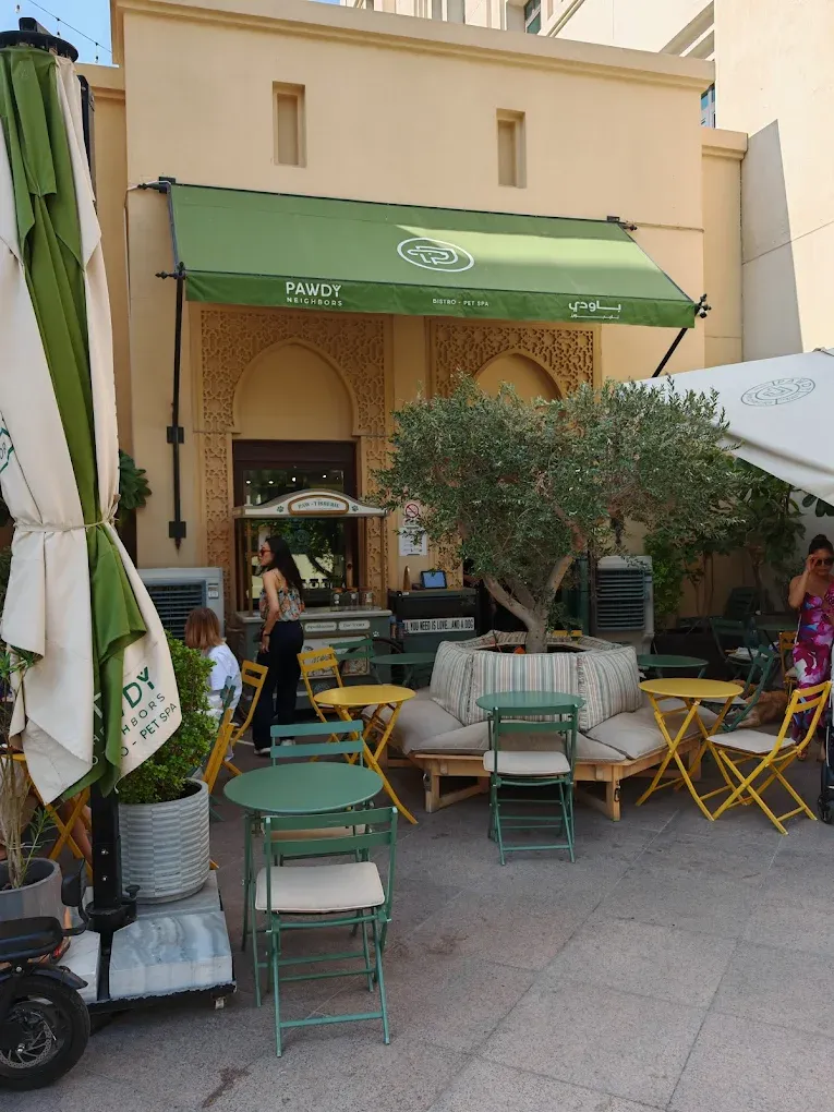 Exterior storefront of Pawdy Neighbors with a green awning and outdoor seating.