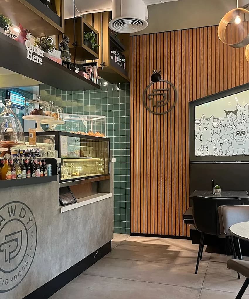 Café counter display with wooden paneling, pendant lighting, and a glass pastry case.
