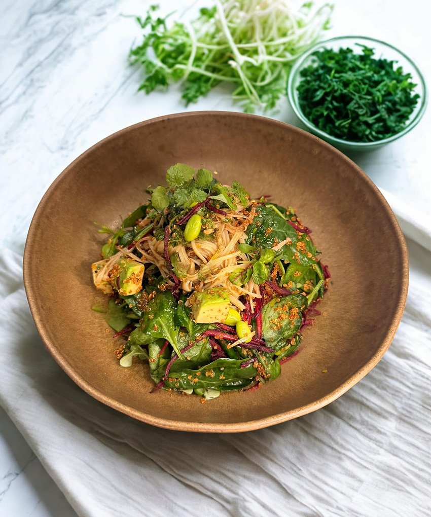 Healthy green salad with avocado, sprouts, and fresh herbs in a wooden bowl at Pawdy Neighbors.