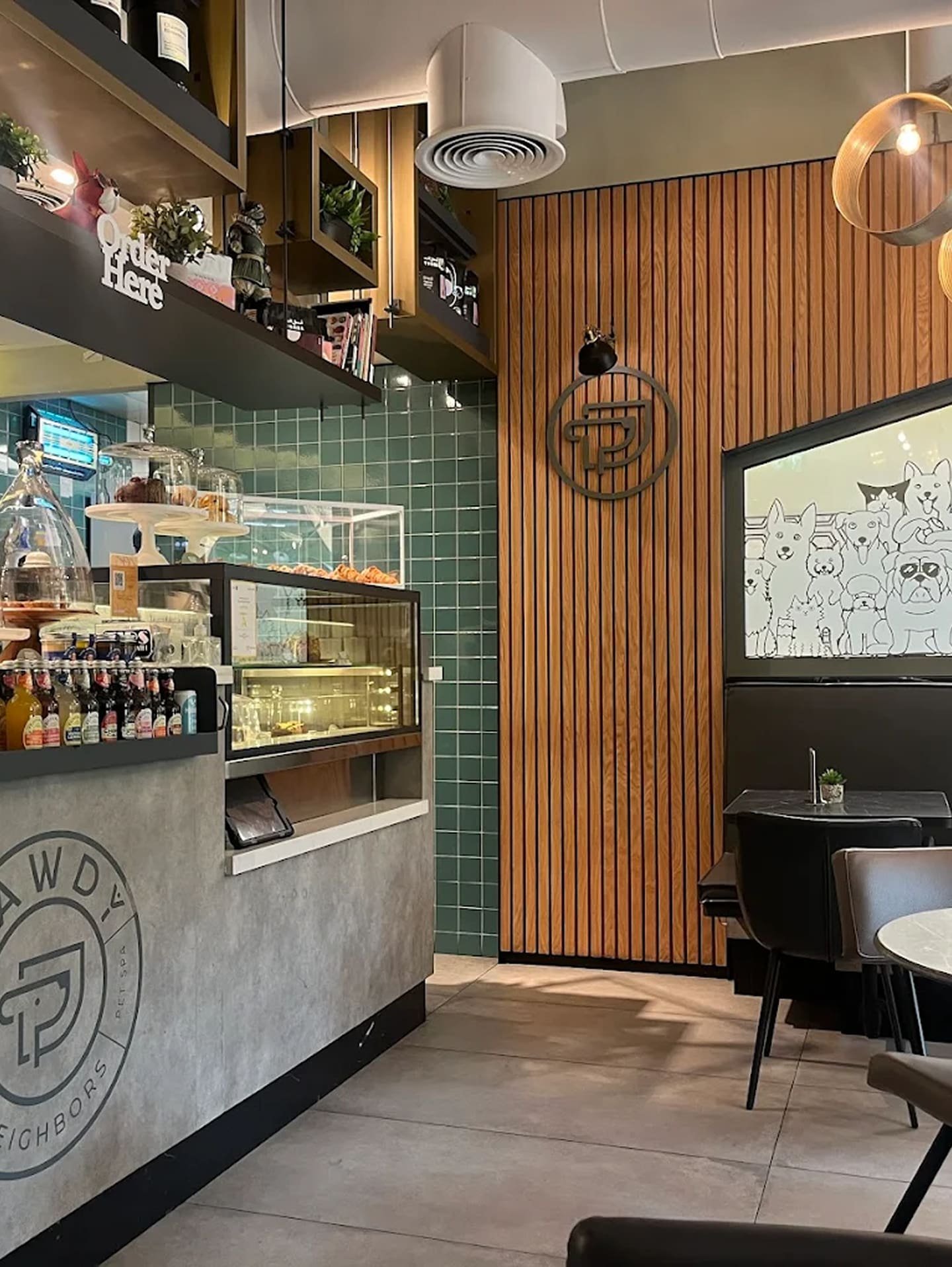 Cozy pet-friendly café with modern design, tiled walls, pastry counter, and indoor seating in Dubai.