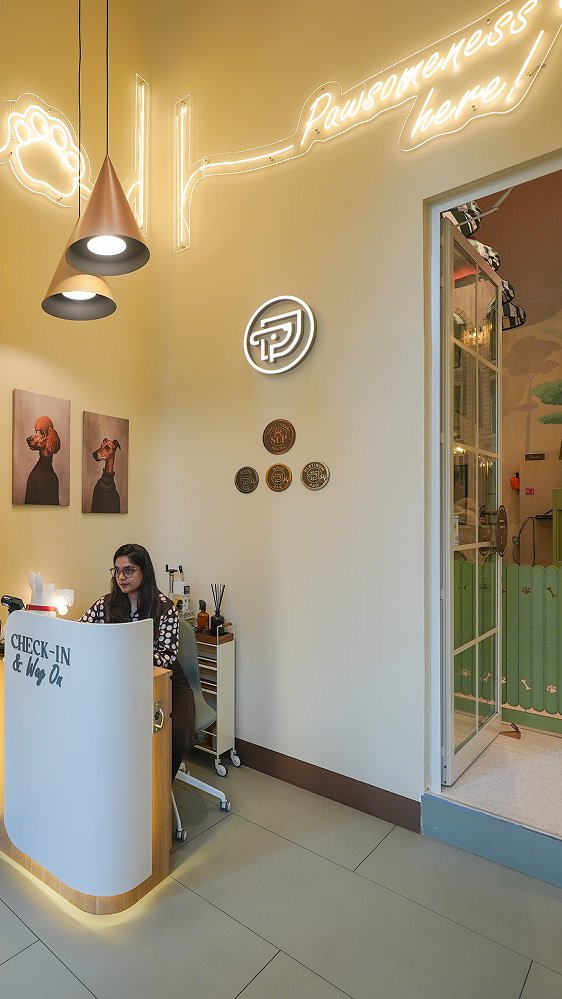 Pawdy Neighbors reception area with neon signage, pendant lights, and a front desk attendant.