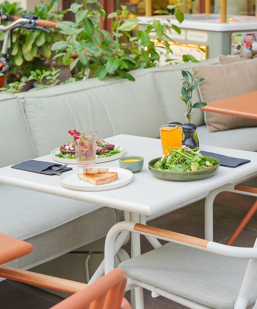 Outdoor café table with a fresh salad and orange juice.