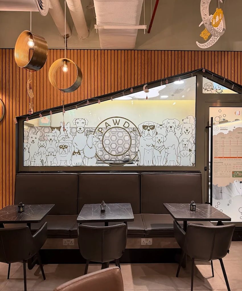 Cozy restaurant interior with wooden wall panels, dark dining tables, and a logo mural.